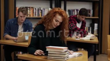 一位年轻的红头卷发女学生正在写论文或准备考试的肖像。 读一本书